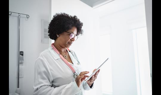 Black female doctor looks at iPad